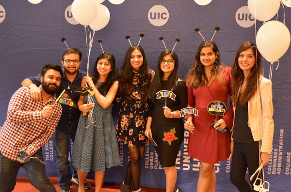 Seven students pose for a photo, smiling with while balloons and graduation headbands.