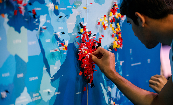 a student is putting a red pin on a large world map