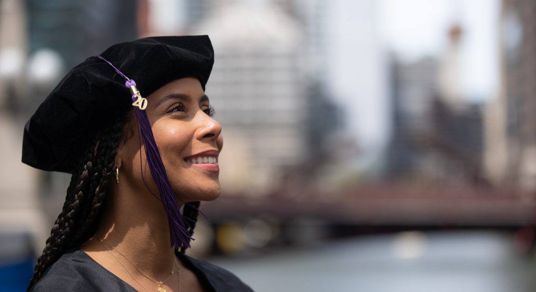 Student in graduation regalia with tassel hanging on right side of face, looking skyward at UIC graduation ceremony in 2021