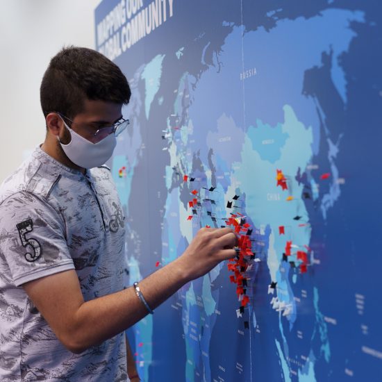 A UIC student pressing a colored pin into a map of the world.