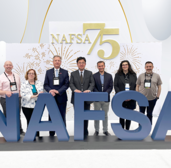 OGE administrators posing in front of NAFSA conference logo
                  