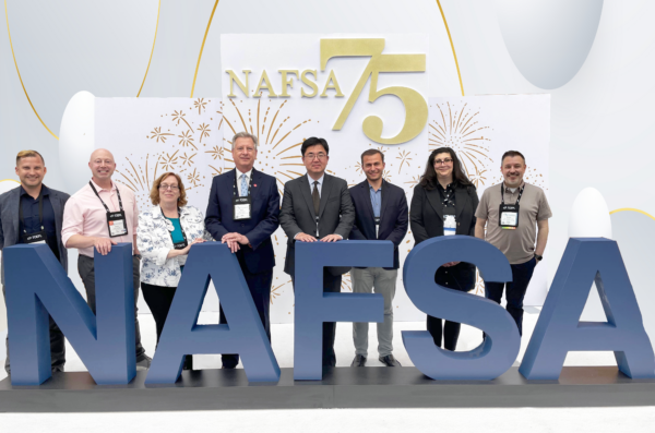 OGE administrators posing in front of NAFSA conference logo