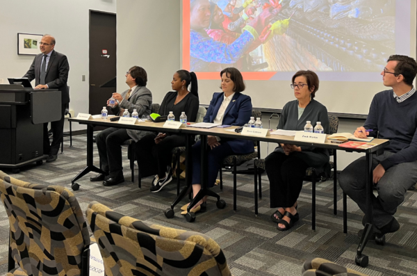 From left to right: Rafik Mansour (speaking at a podium), and Ömür Harmanşah, Alexandra Jones, Allison Davis, Rosa Cabrera, Zack Martin seated at a table and listening to Mr. Mansour