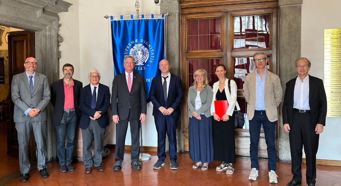 8 University of Pisa representatives posing with Dr Neal McCrillis in the University of Pisa lobby